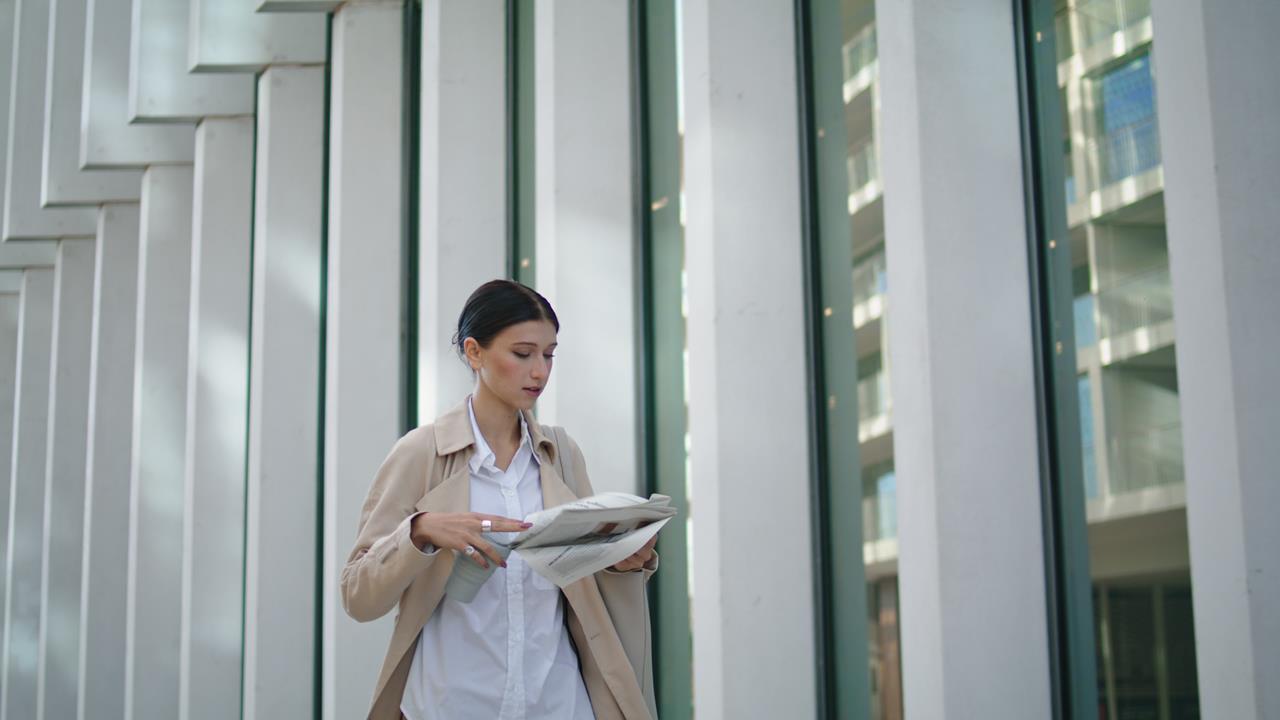 businesswoman-walking-reading-newspaper-on-street-2023-05-04-22-04-41-utc (1)