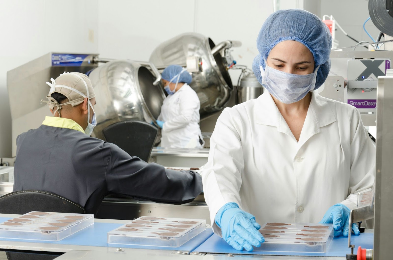 blood bank three people inside factory wearing masks and coats