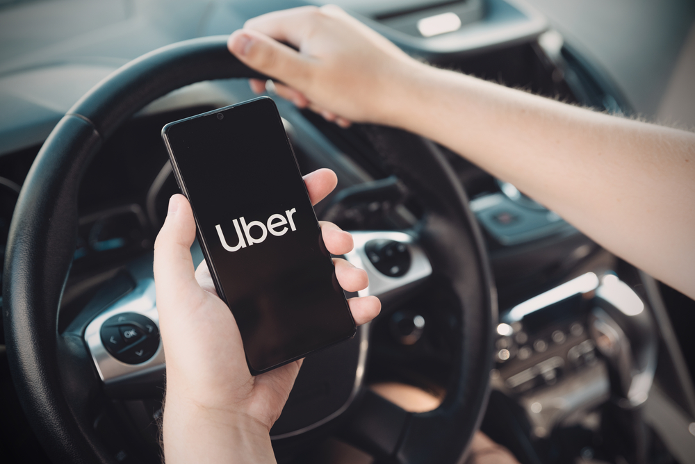 Conductor de Uber en Hungría sostiene un teléfono inteligente en el automóvil